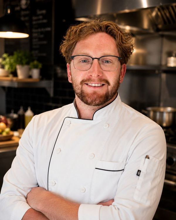 Portrait of Tyler O'Neill, founder of Whetstone Meals, in his chef coat