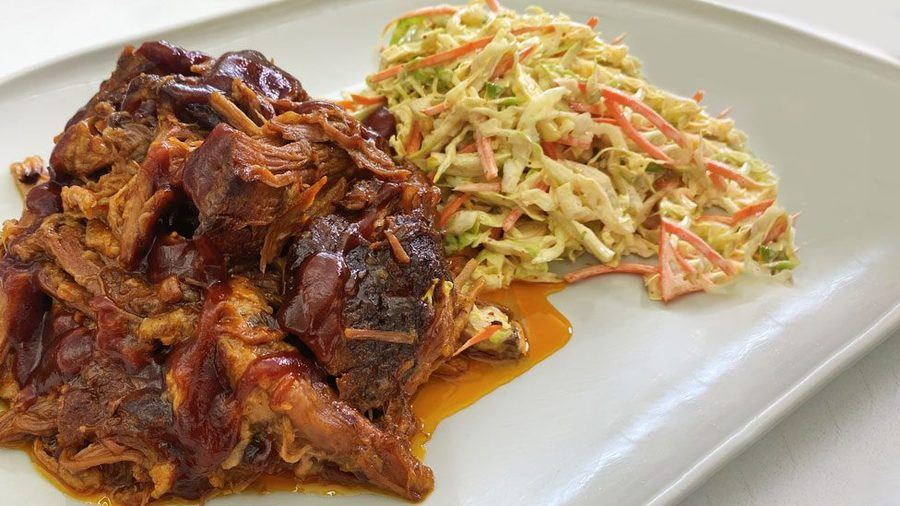BBQ pulled pork with sauce beside a pile of tangy cabbage slaw